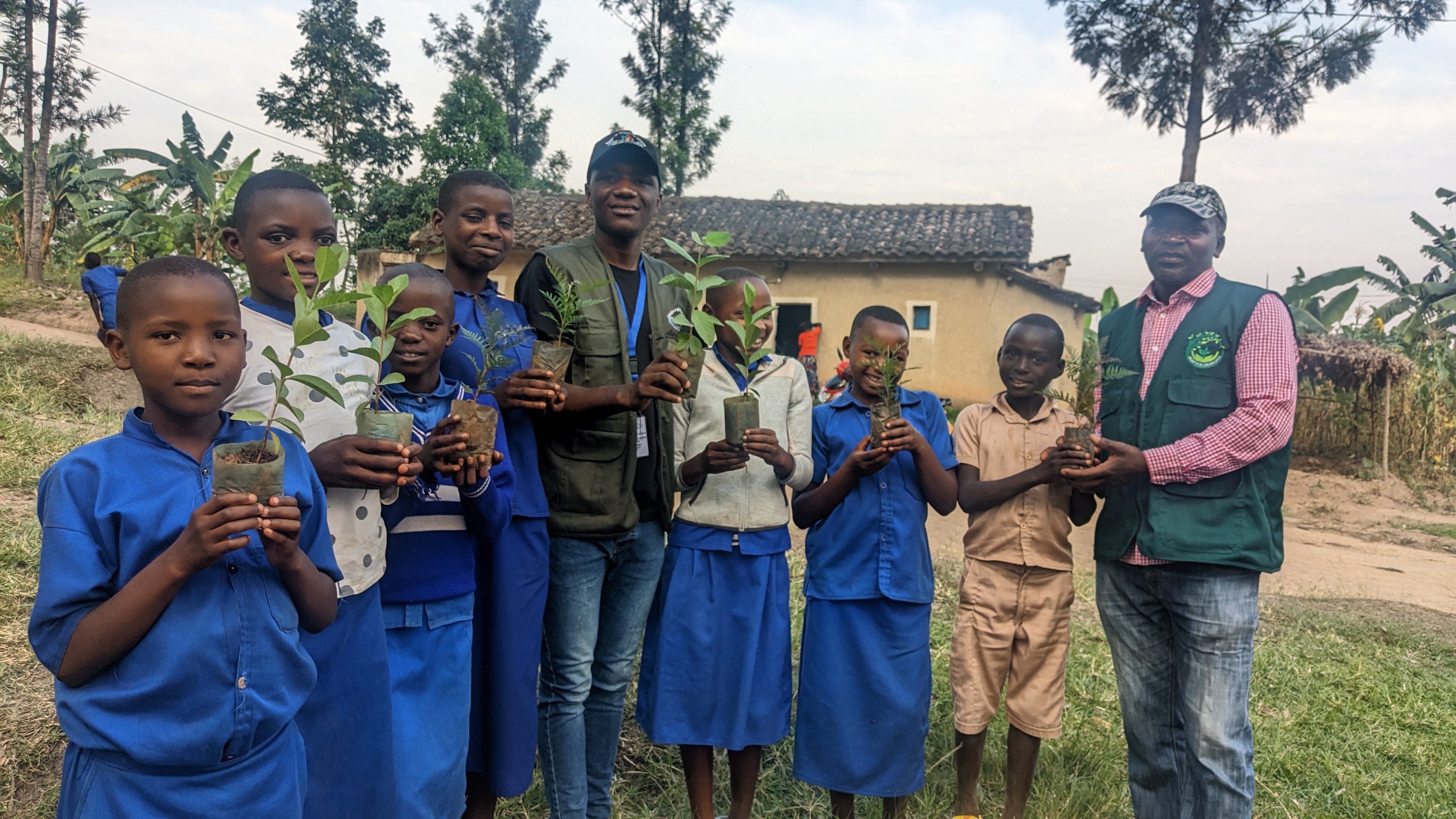 Environmental club students holding seedlings with Green for Life Rwanda staff